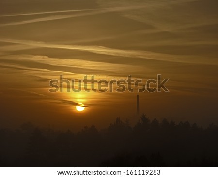 Rising sun emerging out of the fog above the city; Brno