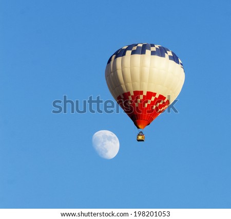 hot air balloon against clean blue sky and moon