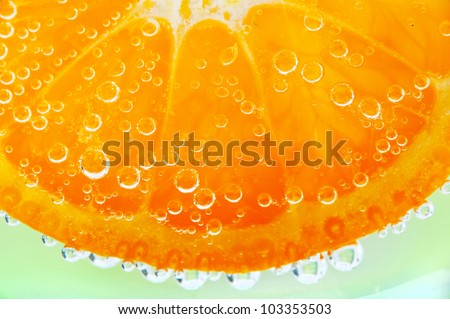 slice of orange in the water with bubbles