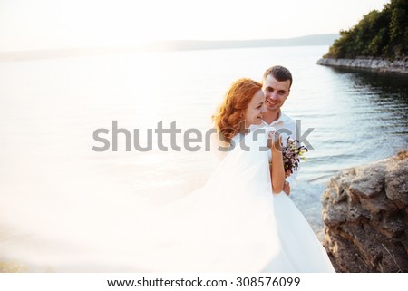 beautiful lovely blonde bride and groom classy on the rocks, amid the sea at sunset.