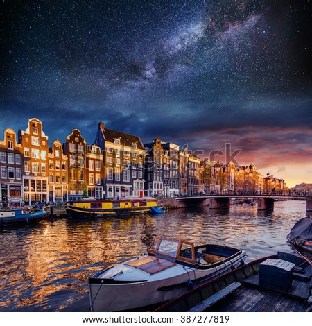 Beautiful night in Amsterdam. Night illumination of buildings and boats near the water in the canal.