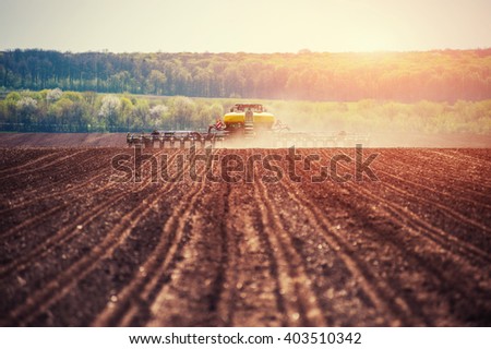 Tractor plowing farm field in preparation for spring planting.