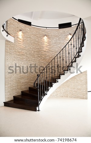 spiral hardwood floor staircase with tiled wall and metal railing