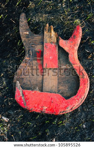 Image electric guitar, which was burned down, on the burned ground.
