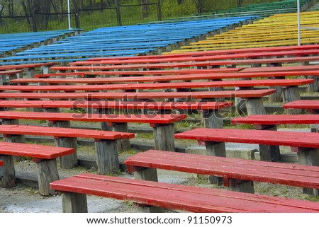 Rows of empty wooden seats at a theater at outdoor.
