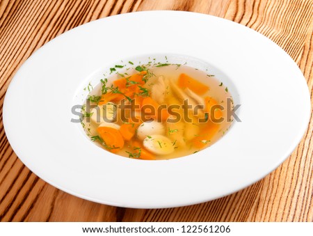 Tasty chicken clear soup on wooden table