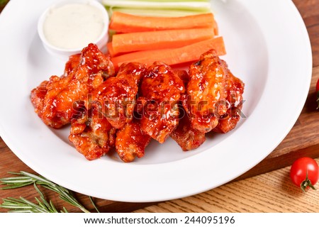 Buffalo chicken wings on plate with sauce, carrots, and celery
