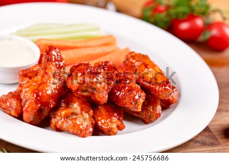 Buffalo chicken wings on plate with sauce, carrots, and celery
