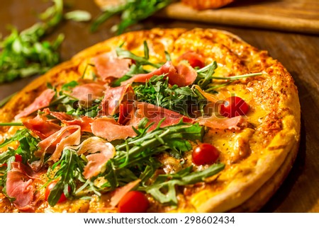 Pizza with prosciutto (parma ham), arugula (salad rocket) and cherry tomatoes