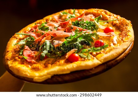 Pizza with prosciutto (parma ham), arugula (salad rocket) and cherry tomatoes