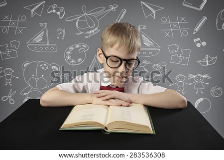 little pupil sitting at the desk and reading a book