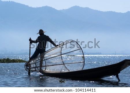 Fishermen on Inle Lake make a living by using a coop-like trap with net to catch fish and are known for their leg rowing style