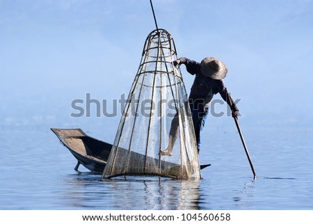 INLE LAKE, MYANMAR - FEBRUARY 17: Fisherman catches fish for food on February 17, 2011 on Inle Lake, Myanmar. Intha people possess the leg-rowing style and the unique coop-like fishing equipment