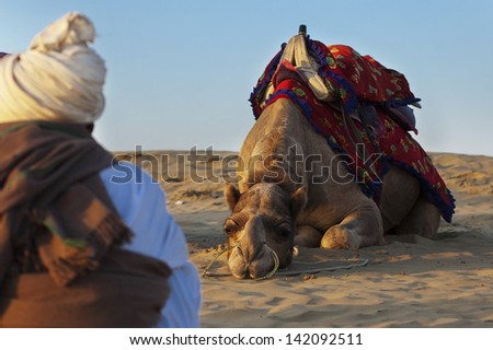JAISALMER, INDIA-FEB 26:  Cameleer waits for tourists at the Sam Sand Dune on Feb 26, 2013 in Jaisalmer, India. Apart from farming, camel riding activity is another income source for desert villagers