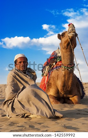 JAISALMER, INDIA-FEB 26: A cameleer waits for tourists at the Sam Sand Dune on Feb 26, 2013 in Jaisalmer, India.Apart from farming, camel riding activity is another income source for desert villagers