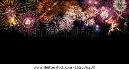 Fireworks in different shaps covering the top part of a black background