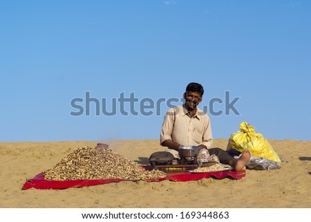 JAISALMER, INDIA - FEB 25:  A street vendor sells baked peanuts at the Sam Sand Dune on Feb 25, 2013 in Jaisalmer, India during the Desert Festival which is held in winter to attract tourists.