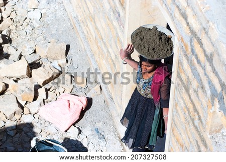 JAISALMER, INDIA - FEB 25: A woman carries ready-mixed cement on her head on a construction site on Feb 25, 2013 in Jaisalmer, India. Construction is the third-largest employer of women in India