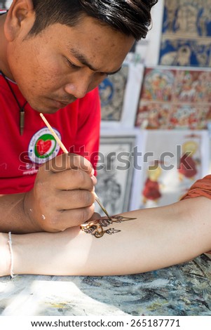BAGAN, MYANMAR - MAR 02: Sand painting artist shows his genuine talent by drawing freehand on a customer\'s arm outside a temple on Mar 2, 2015 in Bagan, Myanmar.