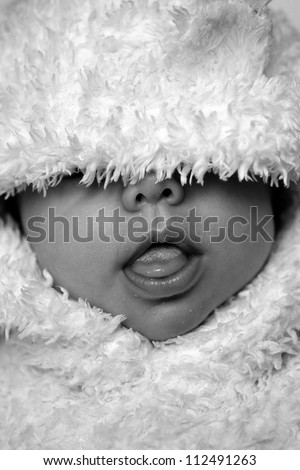 Closeup view to baby sticking one's tongue out in hairy clothes like bear style in black and white