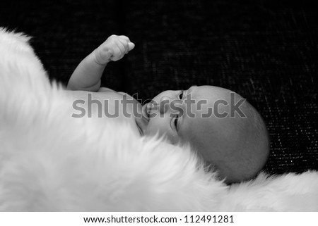 New born baby lying and covered by white fur in black and white