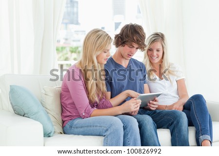 Smiling brother and sisters sit together as they all look into the one tablet pc
