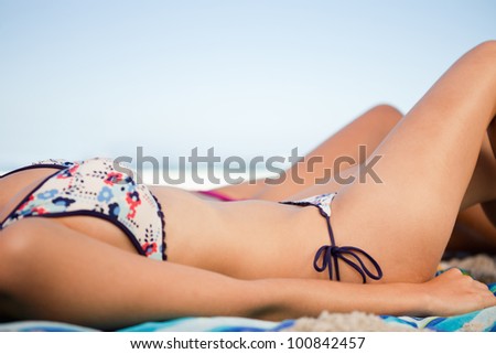 Side view of a young woman bikini on the beach with a friend at her side