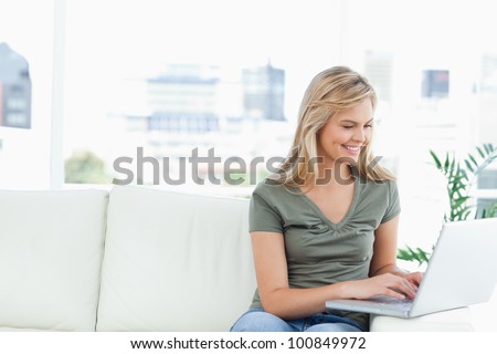 A woman using a laptop on the couch while smiling