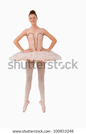 Smiling ballerina standing on her tiptoes against a white background