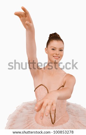 Smiling ballerina with her arms extended against a white background