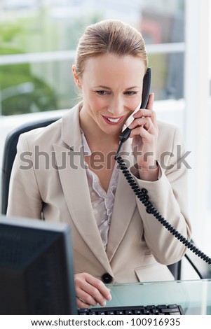Woman in a suit on the phone in her office with city view in background
