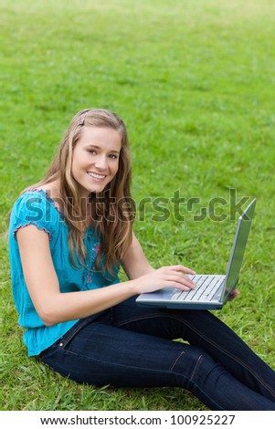 Young beautiful girl looking at the camera while using her laptop in the countryside