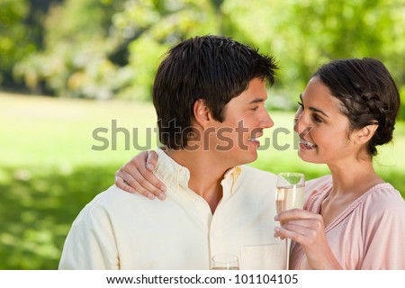 Smiling woman with her arm around her friends shoulder while holding a glass of champagne