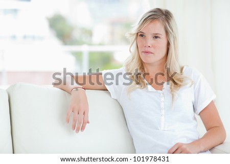 A curious woman looks to the side as she sits on the couch