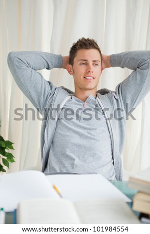 Student stretching while looking away in front of his homework