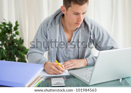 Student doing his homework with a laptop at his desk