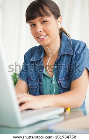 Portrait of a female student doing her homework on her laptop  with music