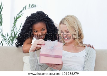 Two smiling women are looking inside of a pink box