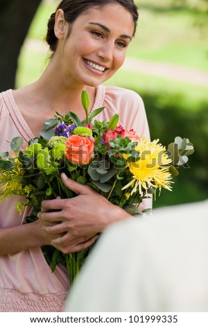 Woman smiling as she holds flowers which have been given to her by a friend
