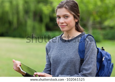 Smiling young woman holding a tablet computer while standing in the countryside