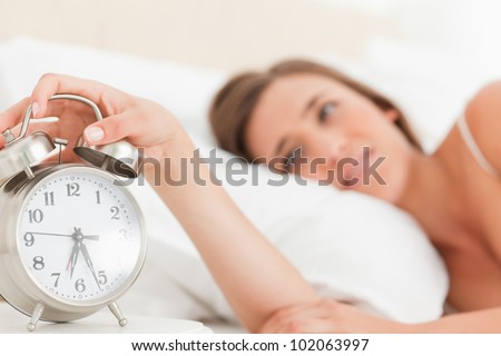 Focus on the alarm clock as woman reaches over to silence its alarm.