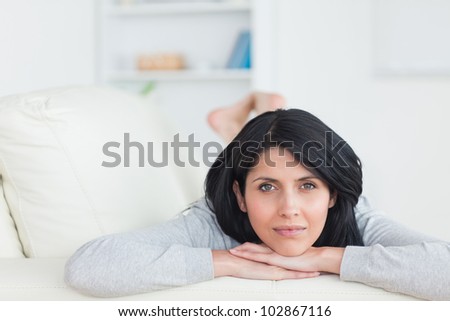 Woman resting on a couch and holding her head with two hands in a living room