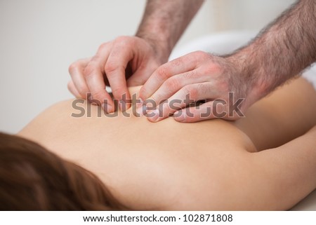 Chiropractor massaging his patient while using his fingertips in a room