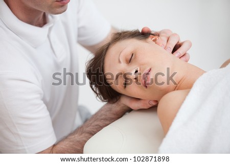 Woman being massaging by the doctor while having the head turn in the side indoor