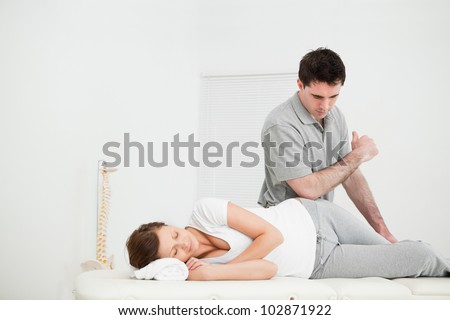 Woman lying on the side while being massaging by her doctor in a medical room