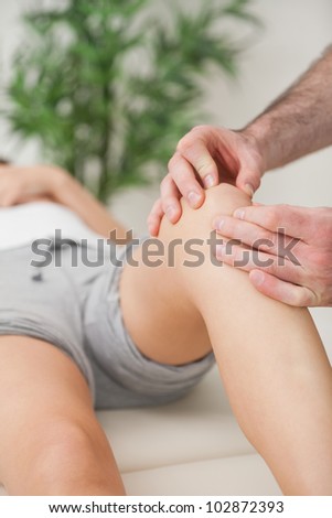 Fingers of a doctor massaging a leg in a room