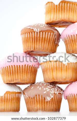 Close up on eight muffins with icing sugar placed in pyramid against a white background