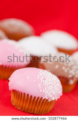 Many muffins with icing sugar on a red tablecloth