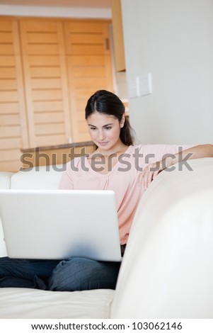 Woman using a laptop while sitting on a sofa indoor