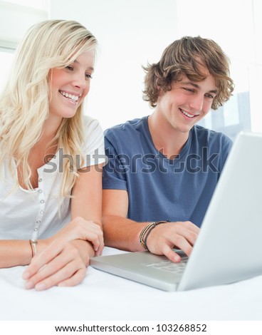 A couple using a laptop to surf the internet as they both smile